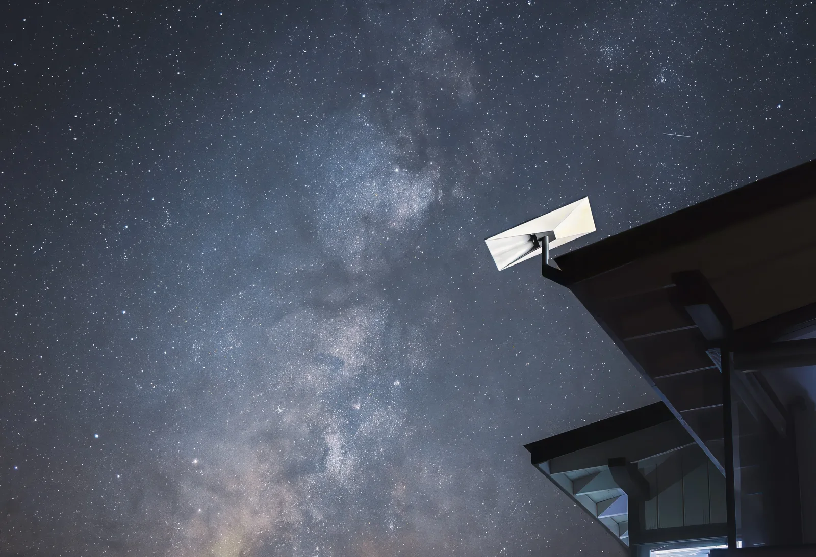 Antena Starlink instalada em um imóvel sob céu estrelado, imagem de referência